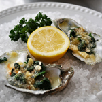 Picture of Oysters Rockefeller, lemon and parsley on a bed of rock salt.