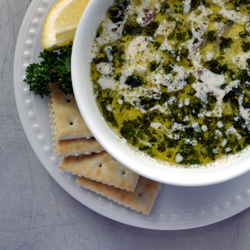 Oyster stew in bowl with crackers, a lemon wedge and parsley.